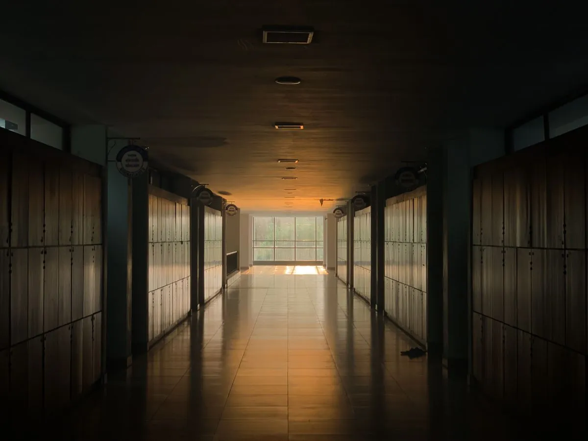 Couloir de circulation d'un bâtiment collectif, portes alignées et lumière en fond